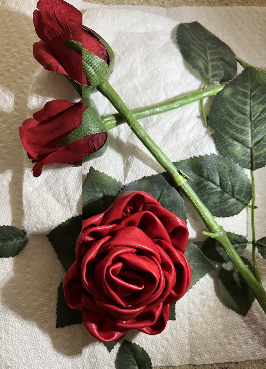 Handmade red satin ribbon rose beside two rosebuds