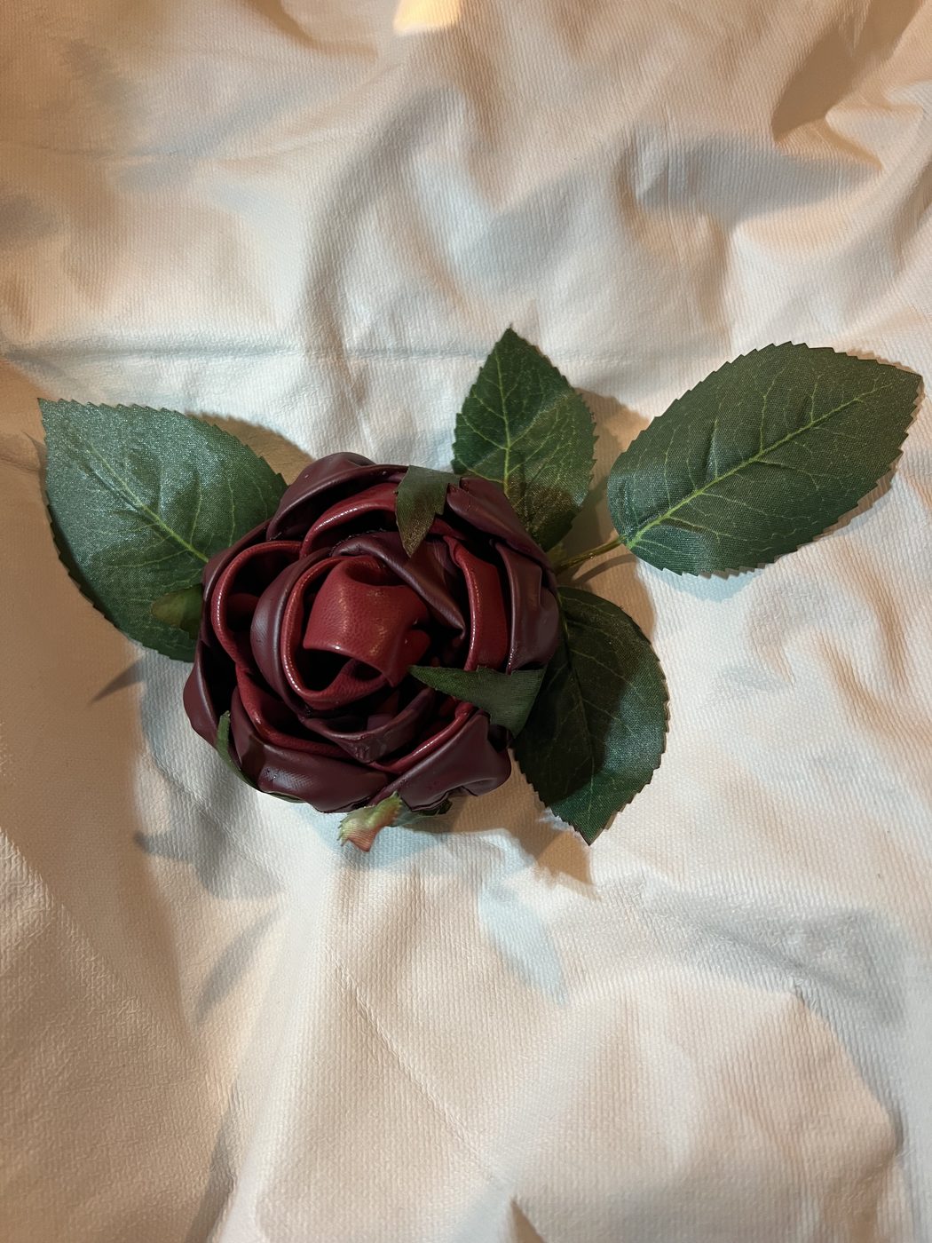 Handmade burgundy ribbon rose on white linen